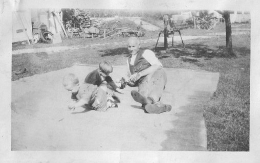 Heinrich Dirks reclining on blanket with two unidentified toddlers
