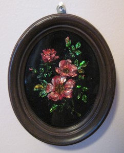 Small tinsel painting of pink flowers in a brown wooden fram