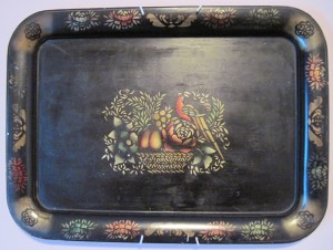 Rectangular metal tray with black background and lip and center painted with plants, fruits, and a bird